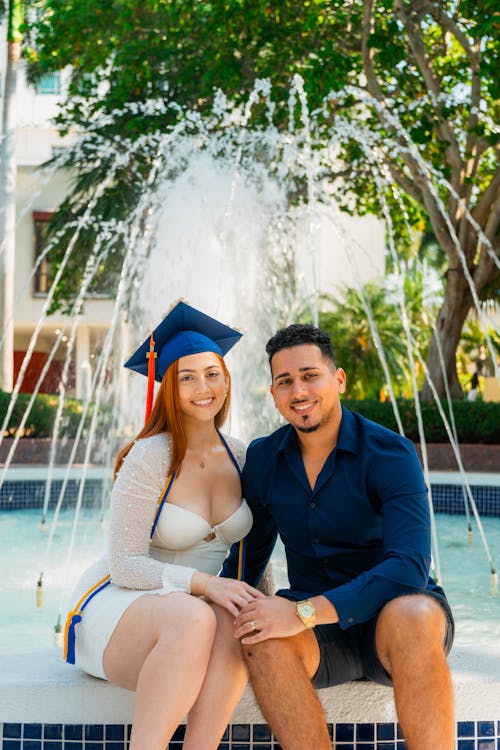 A couple posing for a graduation photo in front of a fountain