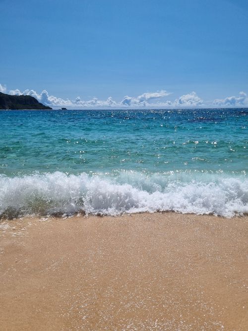 Free A serene coastal scene with clear skies, gentle waves, and sandy shore, perfect for relaxation and nature lovers. Stock Photo