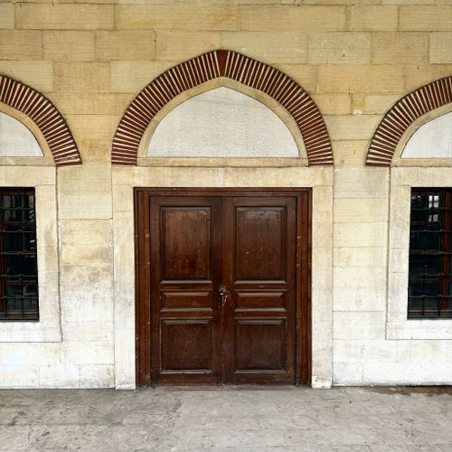 Free A vintage wooden door surrounded by a stone wall and arch brick design, offering a classic urban aesthetic. Stock Photo