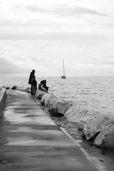 Peaceful black and white scene at an Istanbul pier with a distant sailboat.