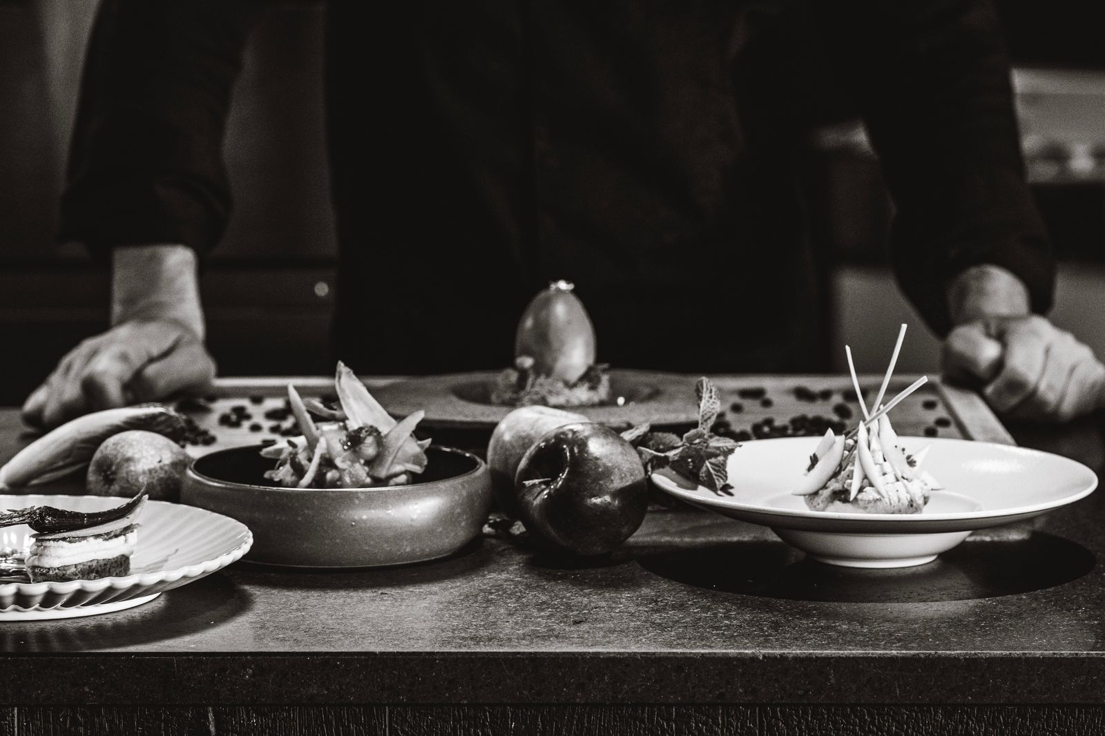 Un chef arrange des plats gastronomiques sur une table dans un cadre e