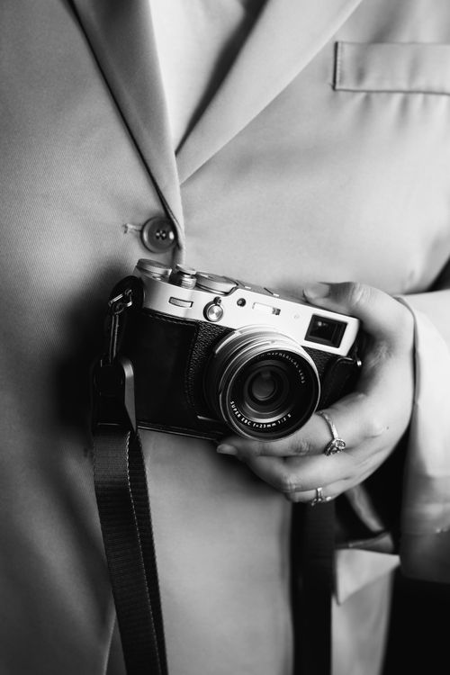 Free Black and white image of a woman holding a vintage film camera, close-up shot. Stock Photo