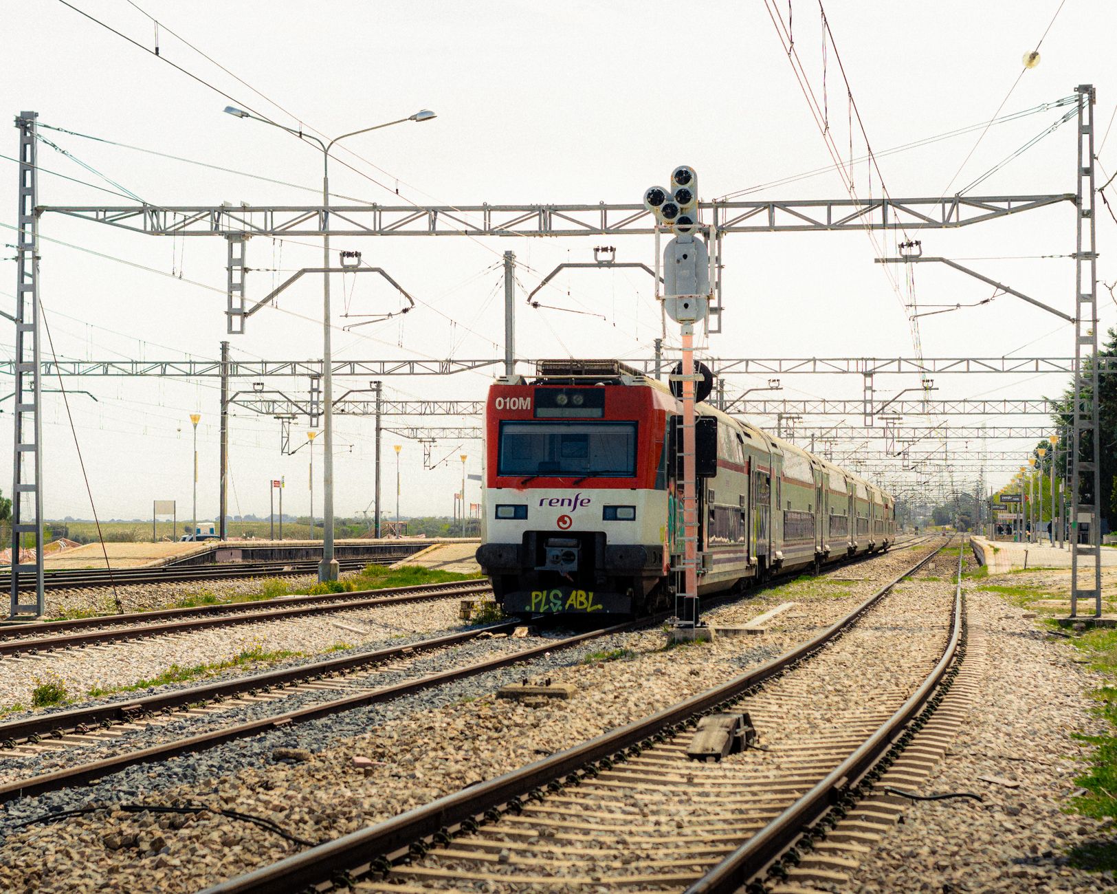 Best Train Between Madrid and Barcelona 6 Renfe train traveling on railway tracks in Madrid on a sunny day.