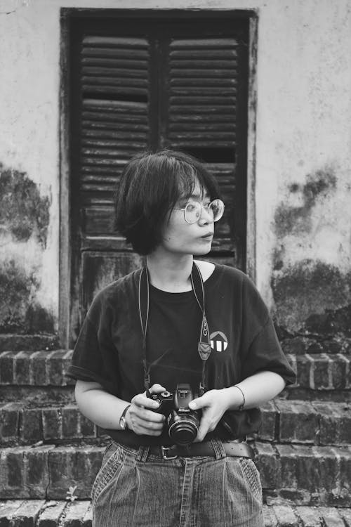 Grayscale Photo of Woman Holding Dslr Camera Facing Sideways
