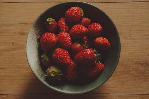 A bowl of strawberries on a wooden table