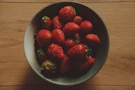 A bowl of strawberries on a wooden table