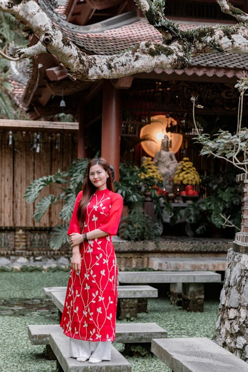 A woman in a red dress standing in front of a pagoda