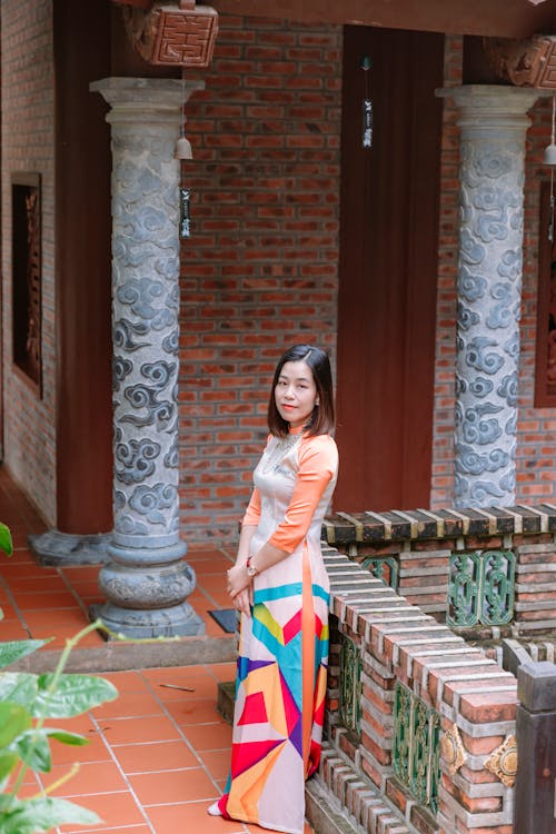 A woman in a colorful dress standing on a stone wall