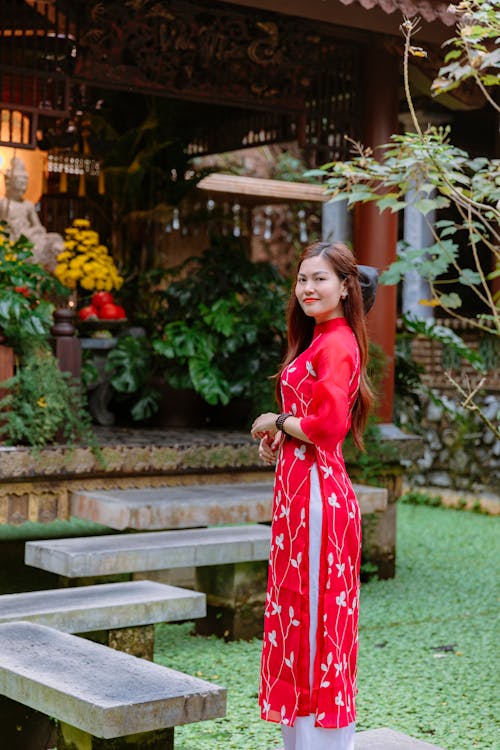 A woman in a red dress standing in front of a garden