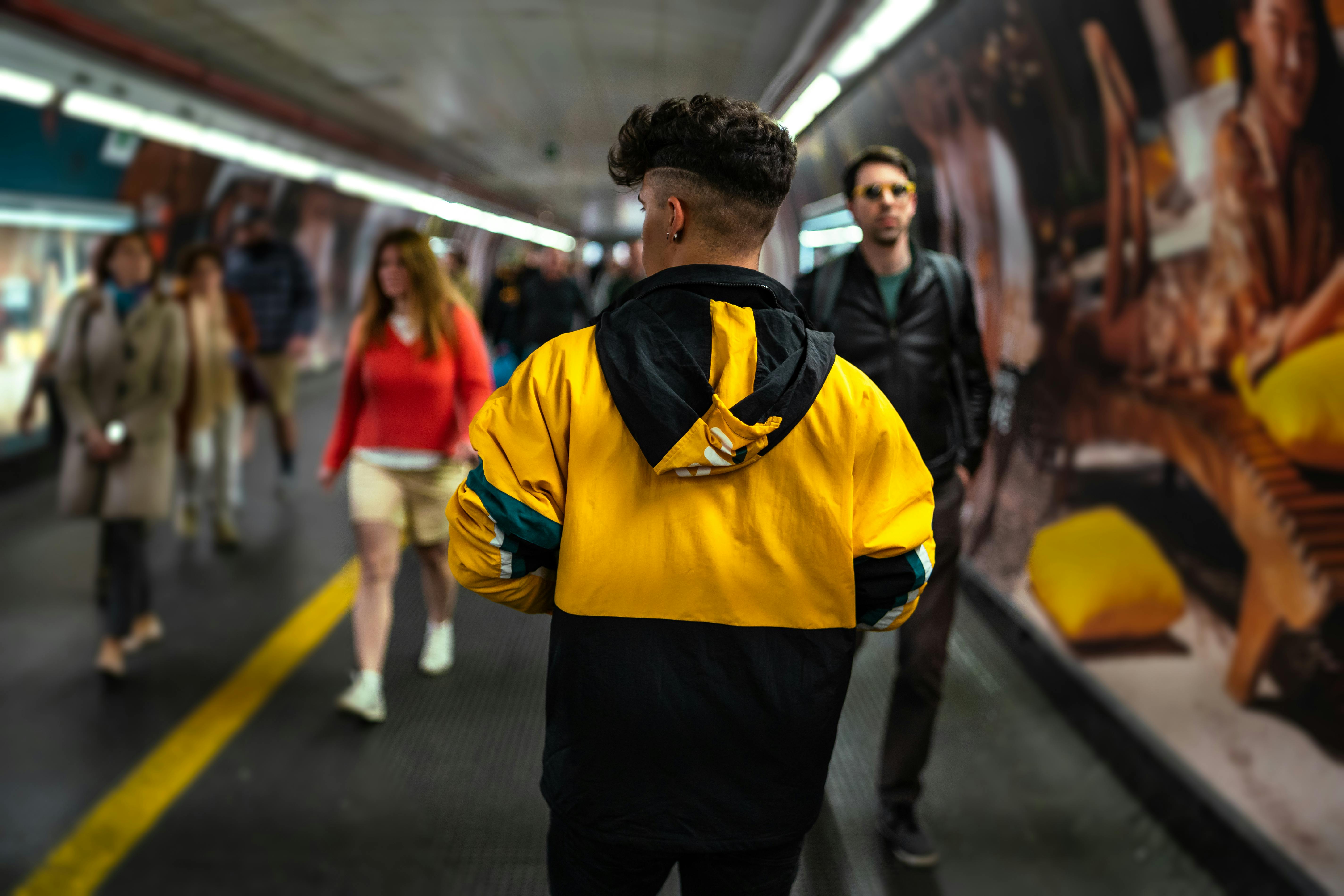 一名身穿亮黄色夹克的年轻人走过罗马繁忙的地铁站