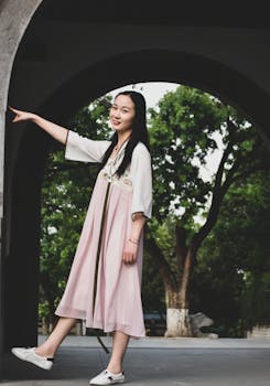 一位身穿时尚夏装的亚洲女子在户外微笑着摆姿势