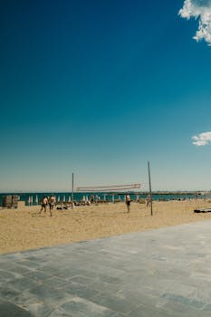 Beach volleyball game on a sunny day in CT, Spain, by the ocean.