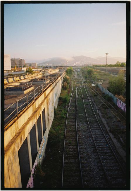 Bird's eye view of railway tracks in Barcelona with mountains in the background at sunset.