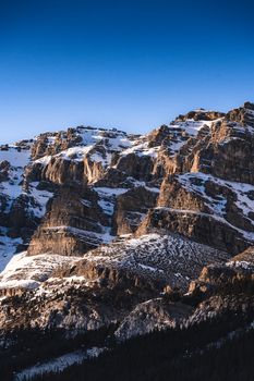 Snow-covered rocky mountains under a clear blue sky in Banff, Alberta.