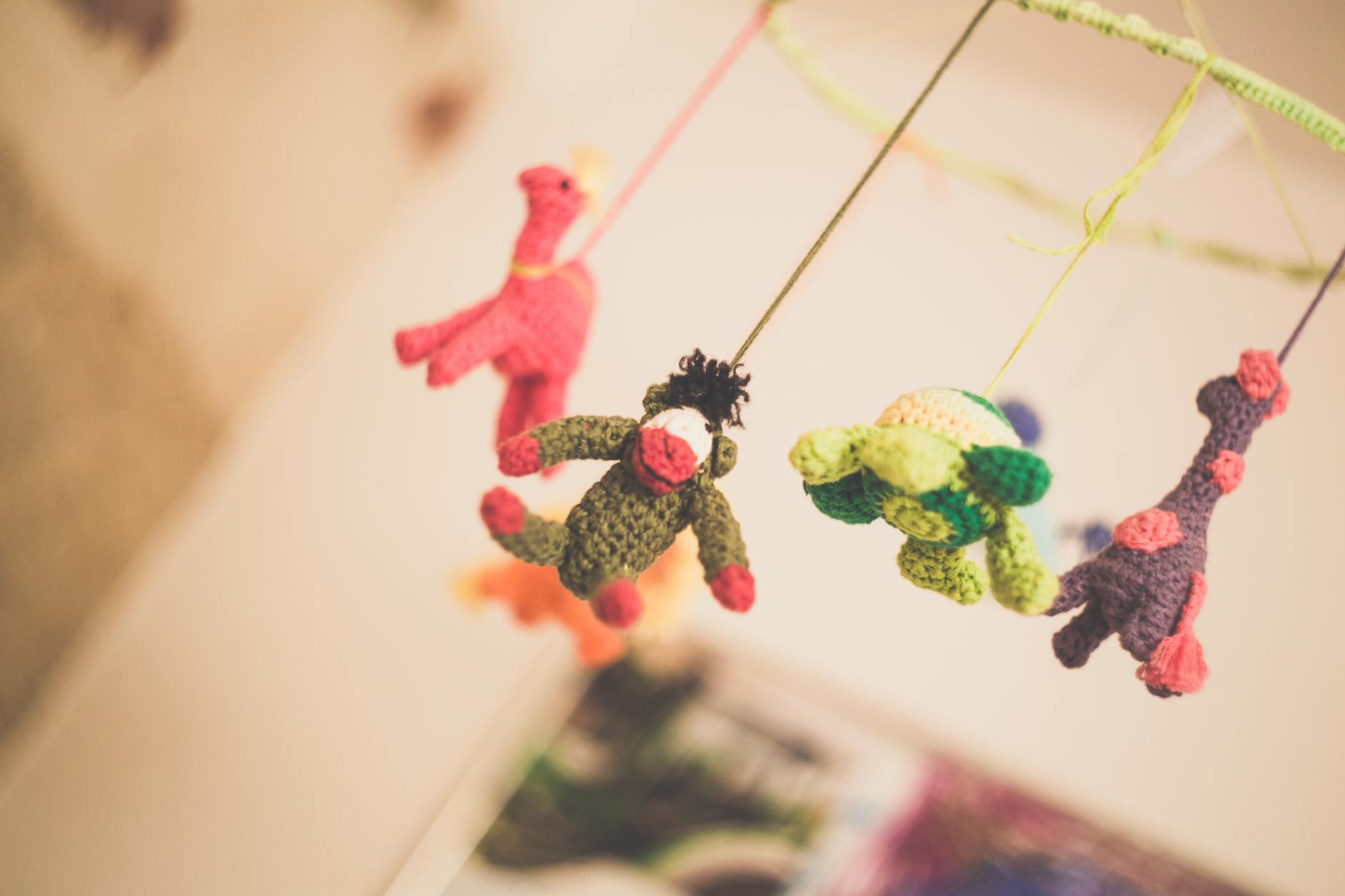 Close-up of a crocheted baby mobile with colorful hanging animal figures, offering sensory stimulation and playful décor for a nursery.