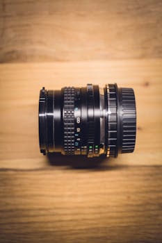 Artistic shot of a vintage camera lens on a wooden background, emphasizing precision and design.