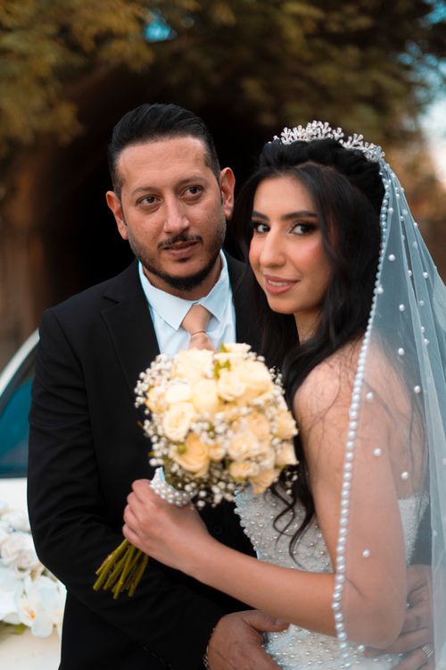 Free A newlywed couple poses elegantly with a bouquet at their wedding in Baghdad, Iraq. Stock Photo