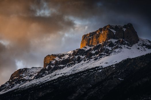 Sunset light on snow-covered mountains in Banff, Alberta showcasing a dramatic winter scene.
