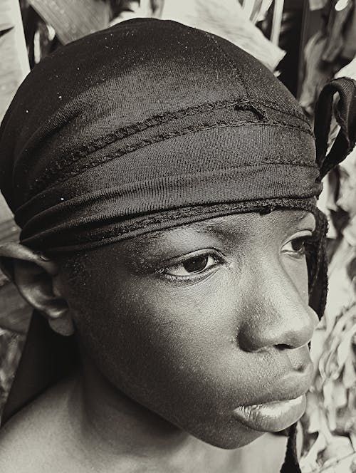 A black and white photo of a young boy wearing a headband