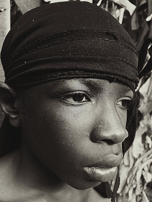 A black and white photo of a young boy with a head wrap