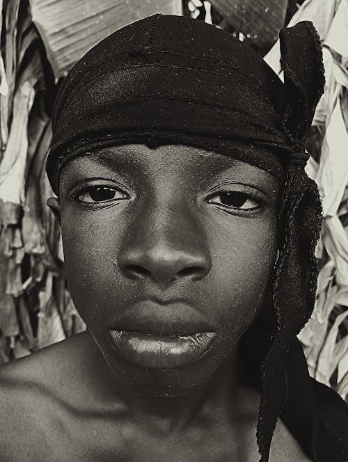 A black and white photo of a young man with a bandana