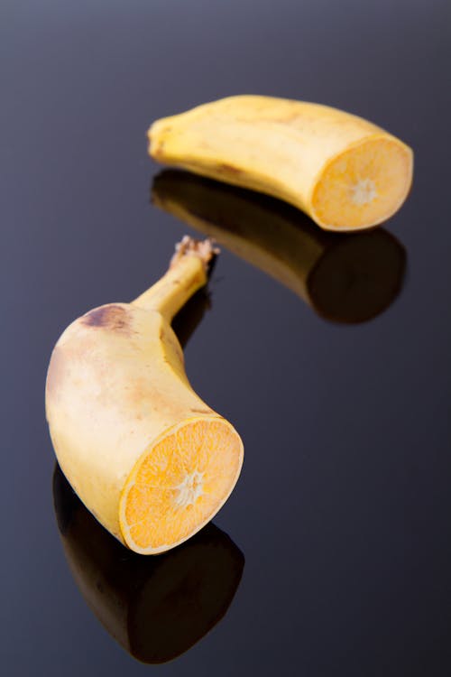 Free In Zwei Gerissene Bananen Auf Schwarzer Oberfläche Geschnitten Stock Photo