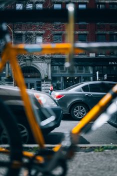 A vibrant city street view with cars and blurred bicycle in the foreground, showcasing urban life.