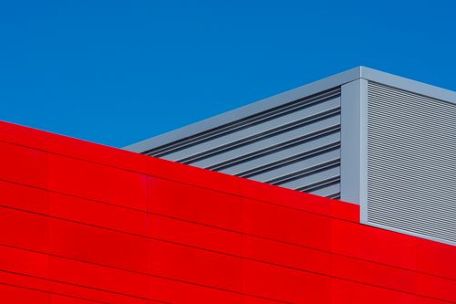 Free Striking geometric patterns on a modern industrial building in vibrant red and grey. Stock Photo