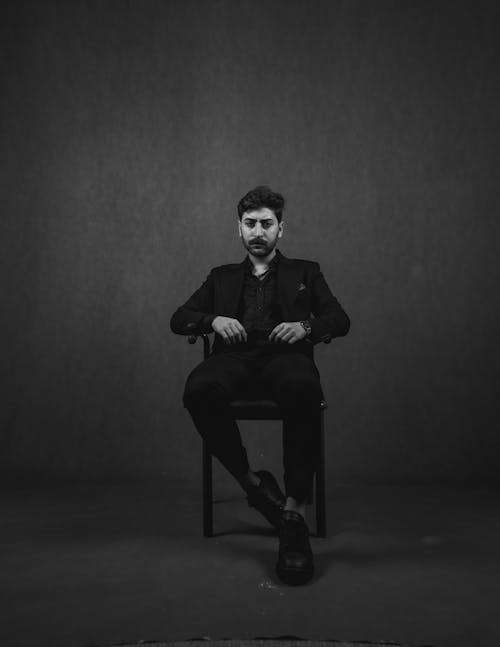 Portrait of a Male Model Wearing a Suit Sitting on a Chair