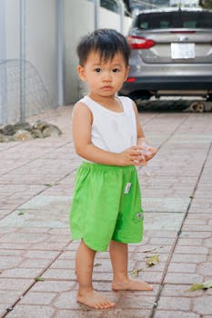 可爱的亚洲幼儿赤脚站在户外的汽车旁