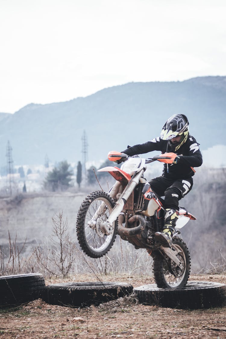 Person Riding Orange And White Dirt Bike