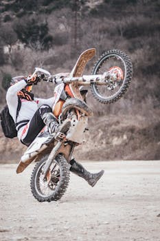 Exciting motocross wheelie on a dirt track, showcasing speed and skill.