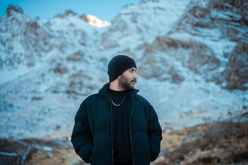 A man in a black jacket standing in front of a mountain
