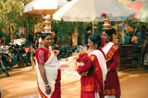 Three women in traditional sari standing under an umbrella