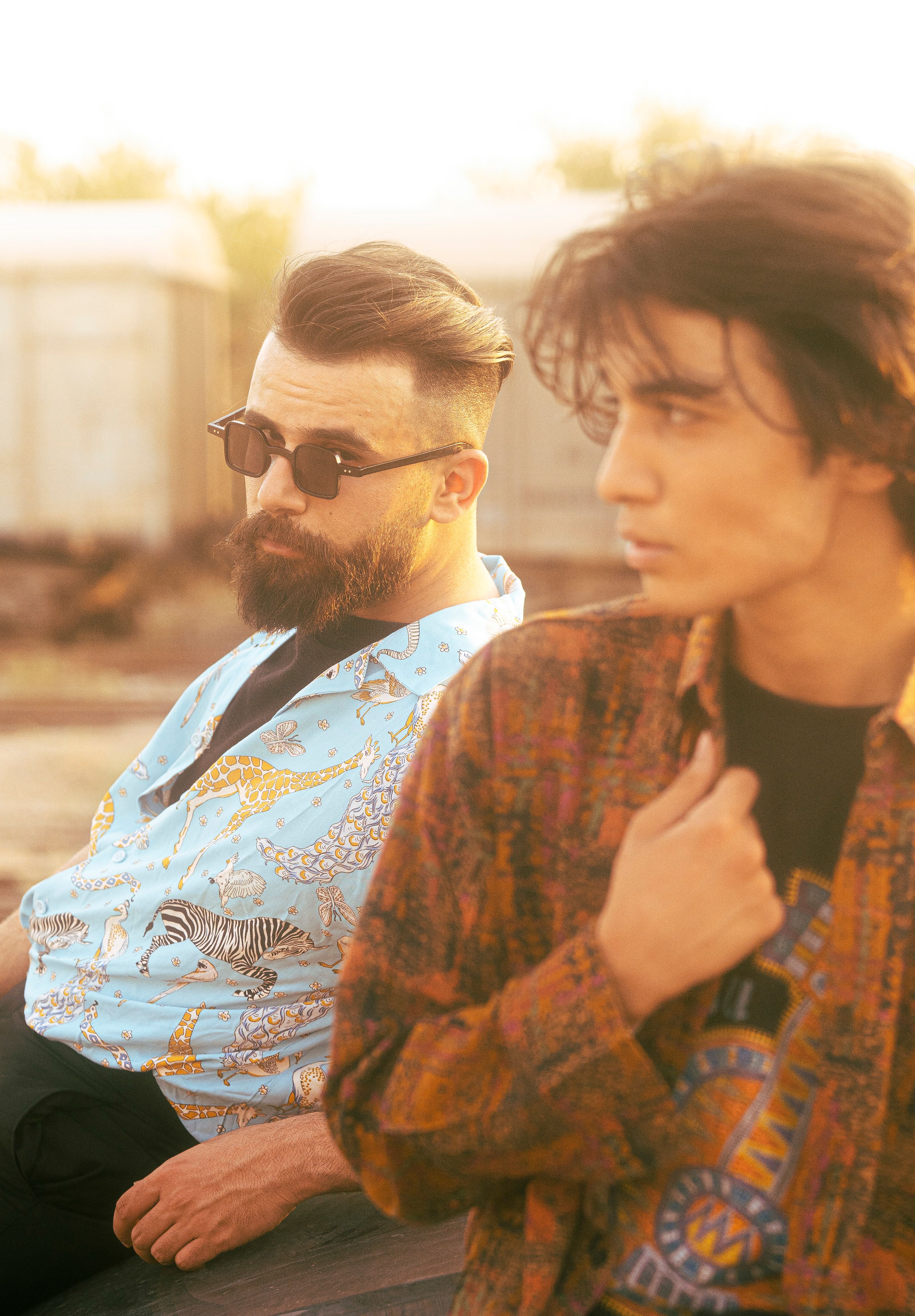 Artistic shot of fashionable men outdoors in Baghdad showcasing printed shirts.