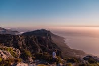 在南非开普敦的桌山上，一个孤独的人走在令人惊叹的日落景色中