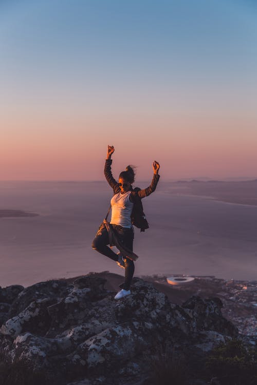 Woman With Hands Up Standing On Rock