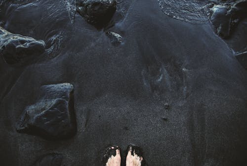 Person Standing on Black Sand