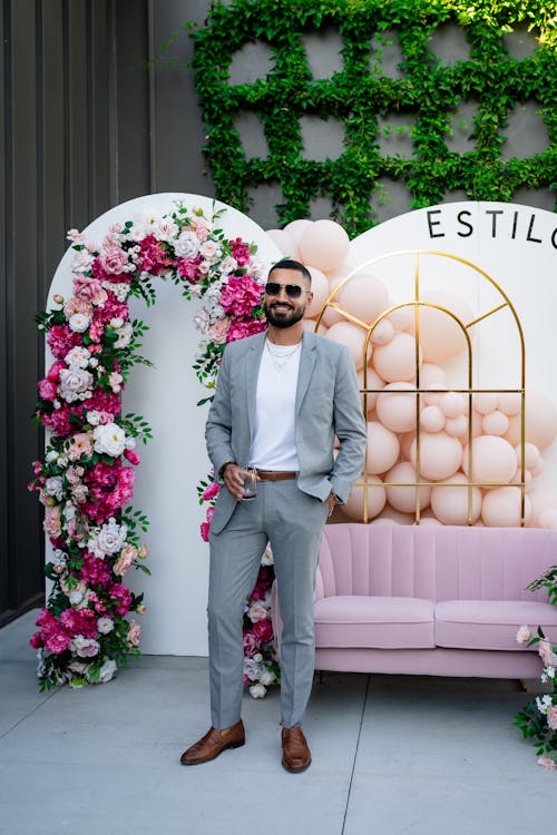A man in a suit standing in front of a pink couch