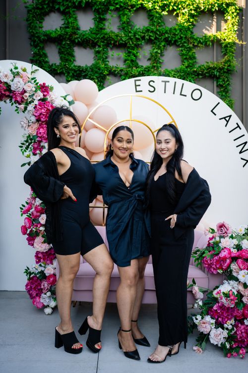 Free Three Latina women elegantly pose at a floral-themed event, showcasing fashion and celebration. Stock Photo