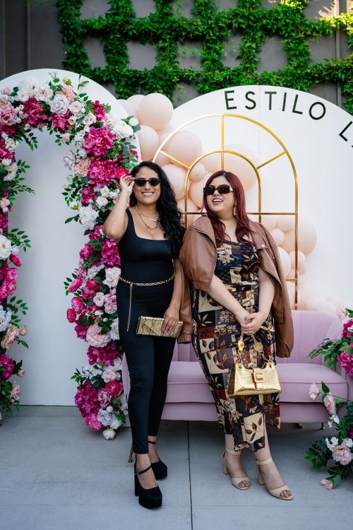 Free Two stylish women pose elegantly with floral backdrop, showcasing fashion and style. Stock Photo