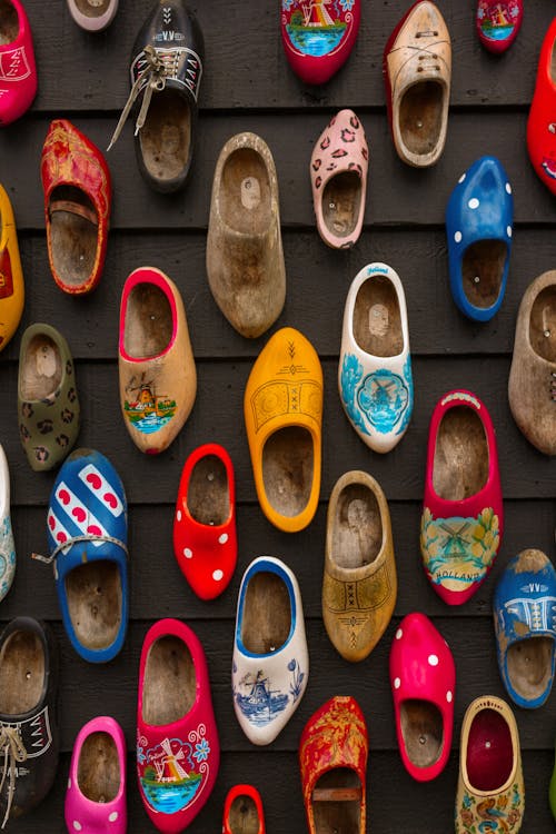 A wall with many different colored wooden clogs