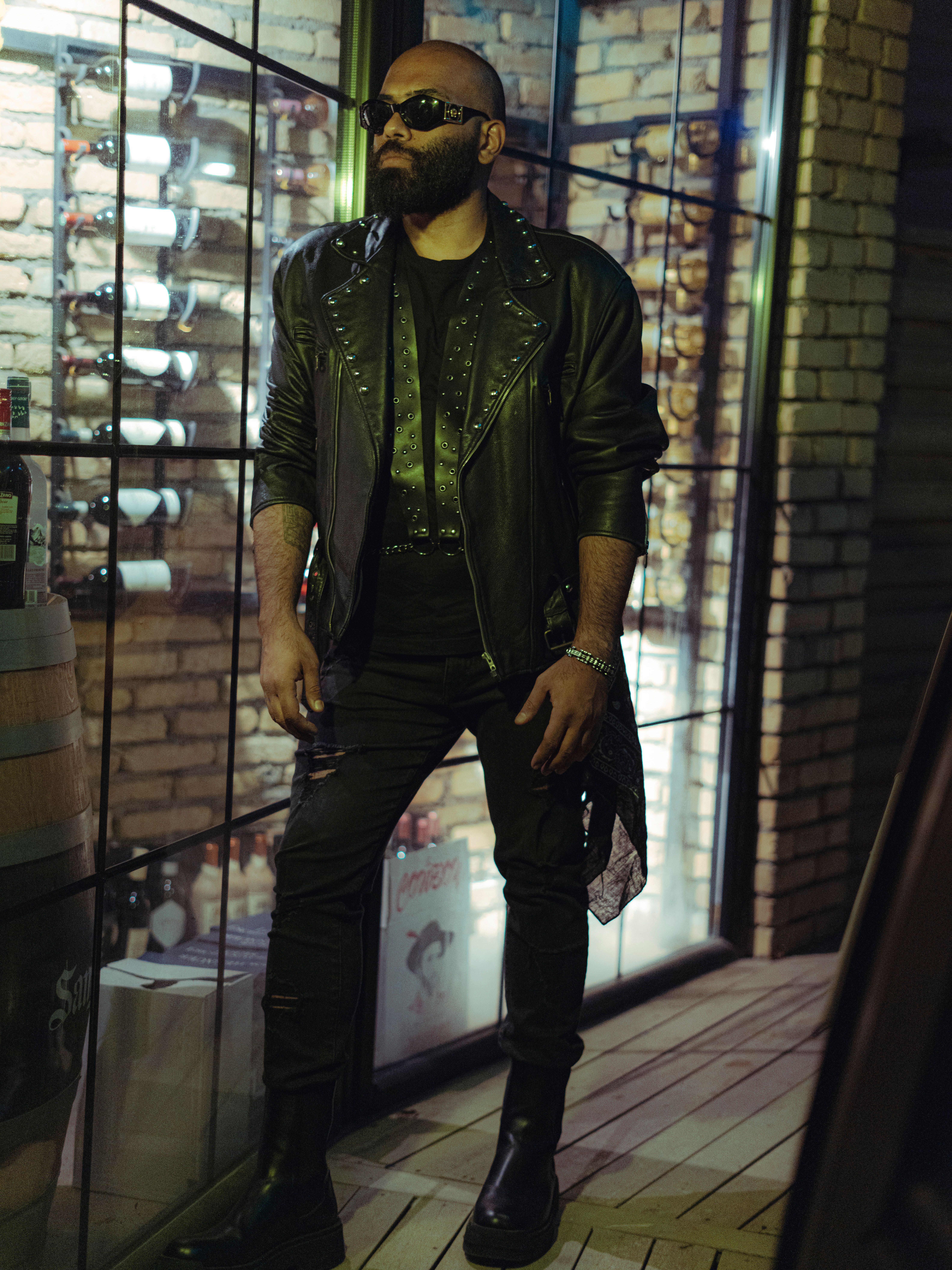Stylish man in leather jacket and sunglasses standing by a wine cellar wall in Erbil.