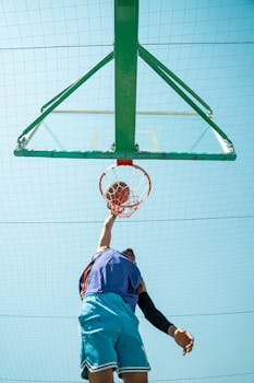 A basketball player performs a dramatic dunk on an outdoor court in Baghdad, Iraq.