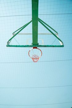 A basketball hoop viewed from below with a clear blue sky in Baghdad.