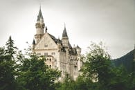 位于巴伐利亚州施万高的哥特式新天鹅堡，四周环绕着郁郁葱葱的绿色植物，散发着历史魅力