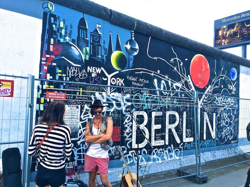 Man Wearing Black Waistcoat and White Tank Tops Standing Near a Mural