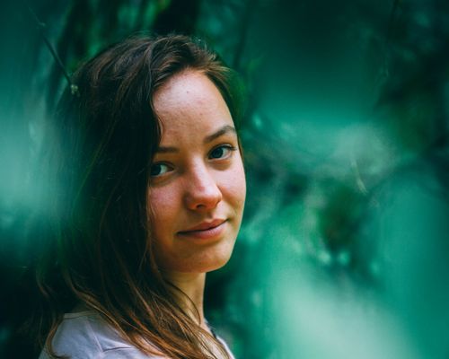 Free Captivating portrait of a woman surrounded by lush greenery, exuding tranquility. Stock Photo