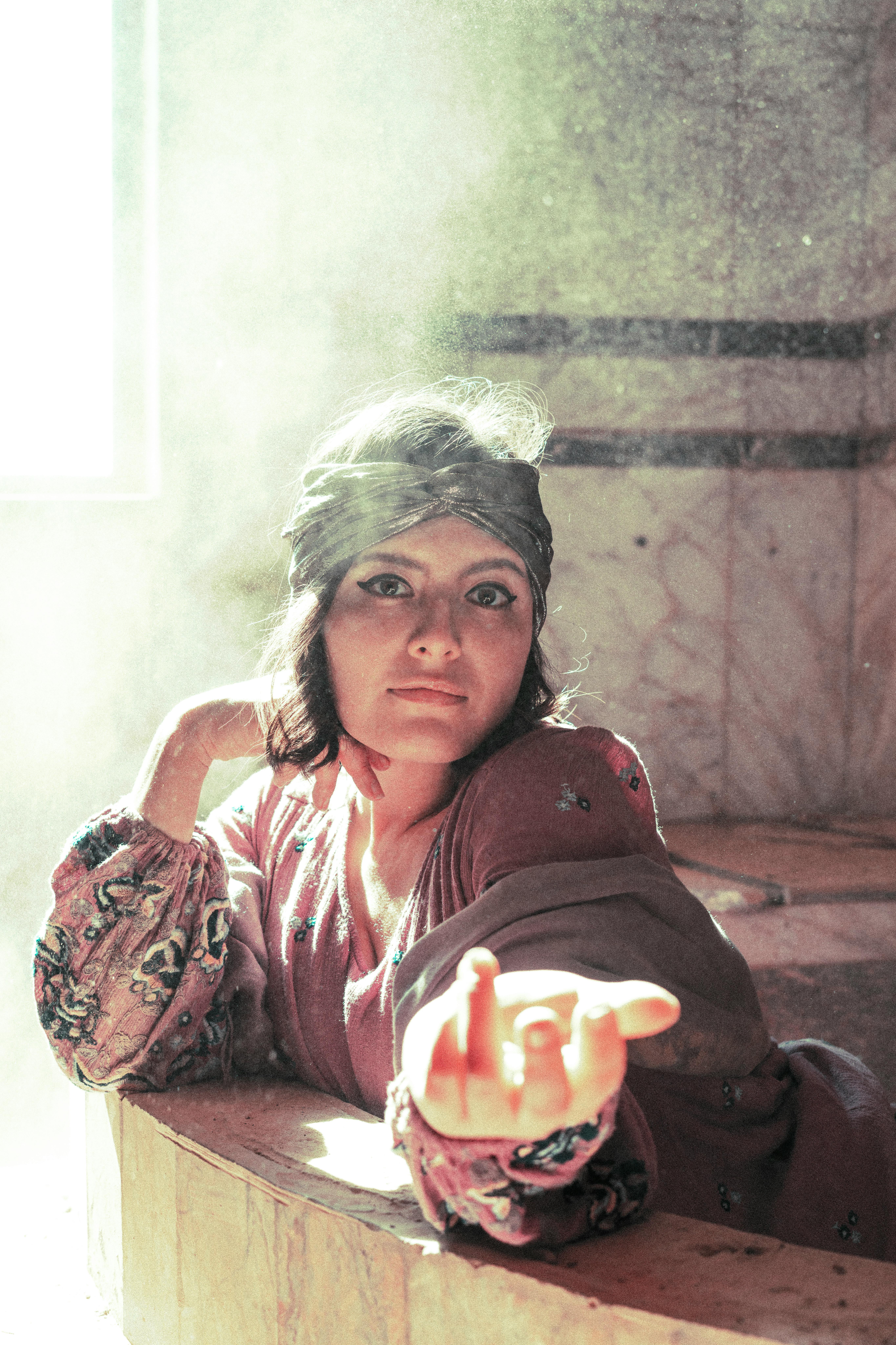 A captivating portrait of a woman indoors, bathed in soft light, with a dramatic pose and expression.