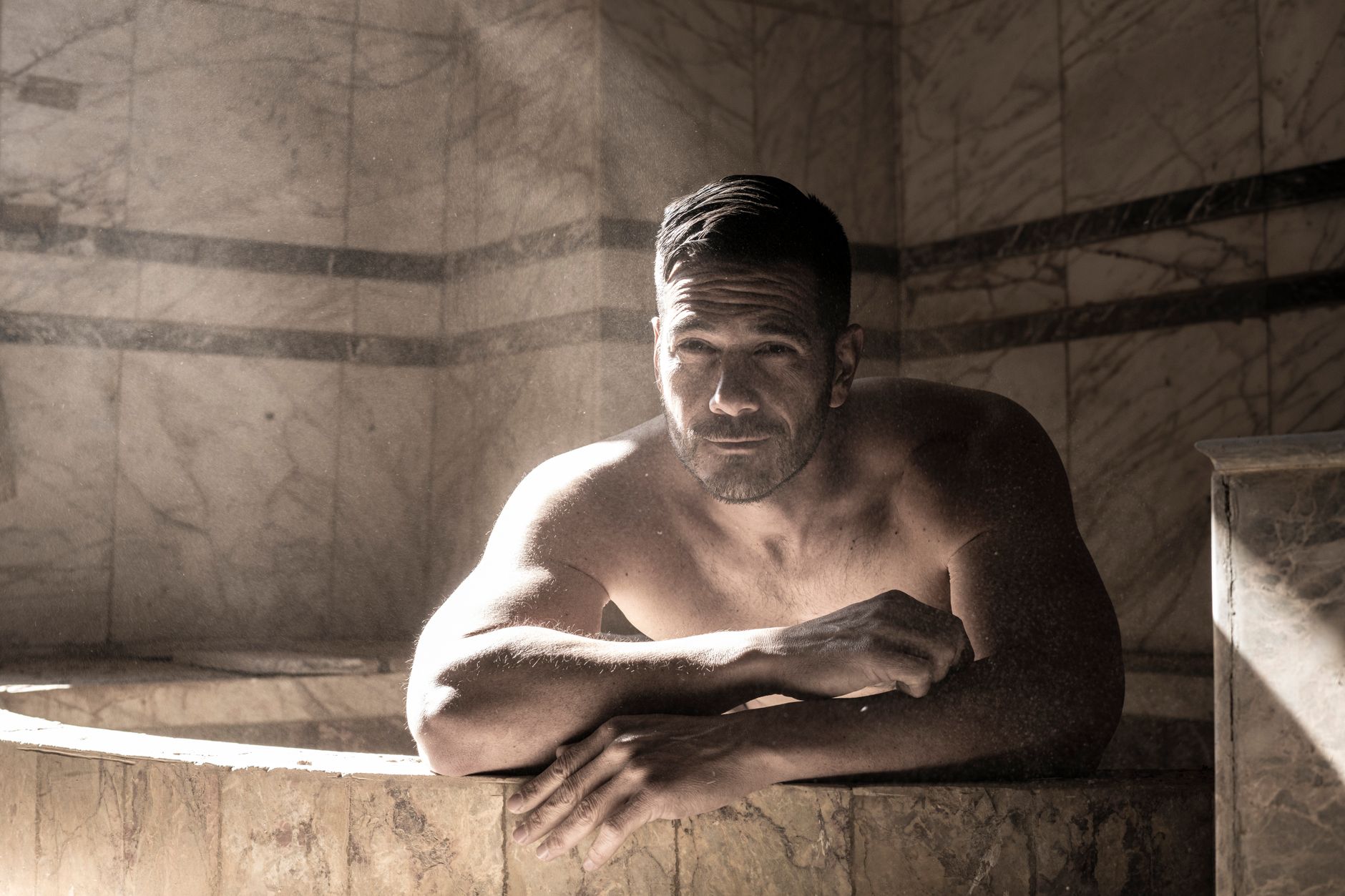 Person relaxing on warm marble in a hammam, sauna vs steam room vs hammam Malta guide